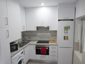 uma cozinha com armários brancos e um frigorífico branco em Botic4 em Cádiz