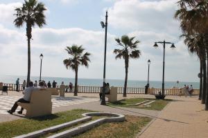 a man sitting on a bench next to the beach at Chipiona CERCA DE LA PLAYA in Chipiona
