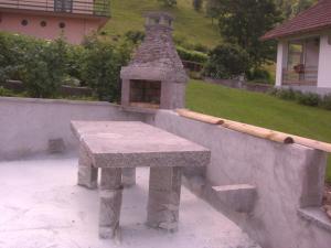 a stone table with a stone oven in a yard at Chalets les Marcels in La Bresse