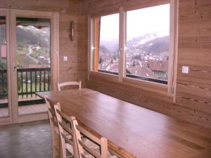 un comedor con una gran mesa de madera y ventanas en Chalets les Marcels, en La Bresse