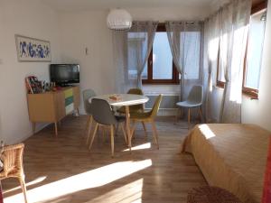een woonkamer met een bed en een tafel en stoelen bij la maison de Lucie in Surbourg