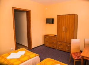 um quarto com duas camas, um armário e uma mesa em Penzion Fako em Liptovský Mikuláš