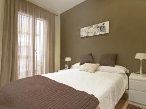 um quarto com uma grande cama branca e uma janela em Apartamento Céntrico em Ripoll
