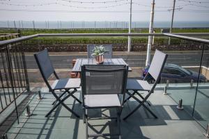 een tafel en stoelen op een balkon met een auto bij Stay in Blackpool