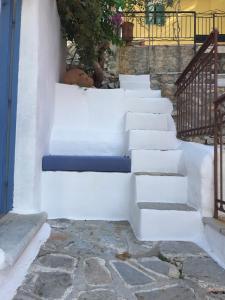 a set of white stairs with a blue seat at Plesner House, Symi Greece in Symi