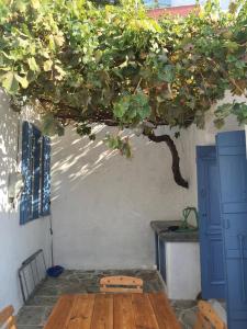 a wooden table under a tree next to a building at Plesner House, Symi Greece in Symi