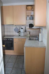 a kitchen with wooden cabinets and a sink at Gönnerbude Fehmarn in Fehmarn