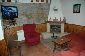 a living room with a fireplace and a red chair at El Tormal in Navalonguilla