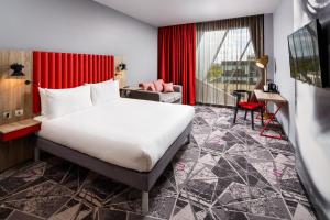 Habitación de hotel con cama grande y cortina roja en ibis Styles London Ealing en Ealing
