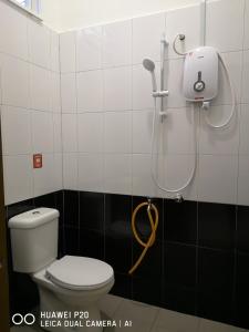 y baño con ducha, aseo y cabezal de ducha. en Zuriana Ashraf Homestay Kota Bharu, en Kota Bharu