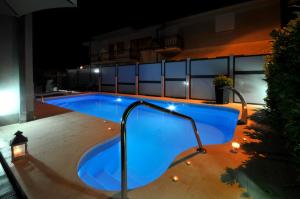 a swimming pool at night with lights on a building at Apartments & Rooms Villa Maslina in Trogir