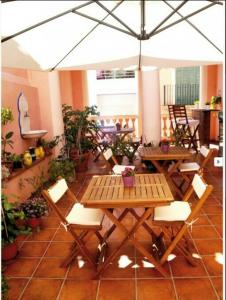un patio con 2 mesas, sillas y una sombrilla en Hostal Parellades, en Sitges