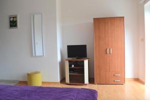 a bedroom with a bed and a tv and a wooden cabinet at Apartments Dragun in Podstrana