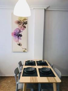 una mesa de madera con sillas y una pintura en la pared en Katy Apartments, en Playas de Orihuela