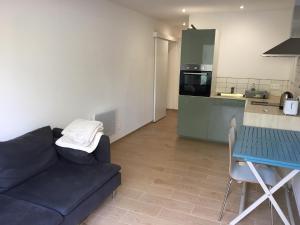 sala de estar con sofá, mesa y cocina en Les Mimosas Apartments, en Villelongue-dels-Monts