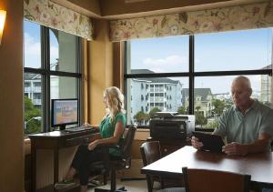 Sea Crest Oceanfront Resort في ميرتل بيتش: رجل وامرأة يجلسون في مكتب وبه جهاز كمبيوتر