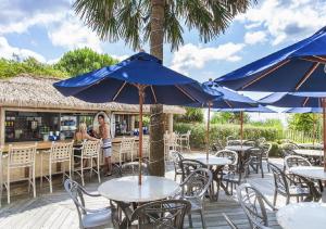 two women standing at tables and chairs with blue umbrellas at Sea Crest Oceanfront Resort in Myrtle Beach
