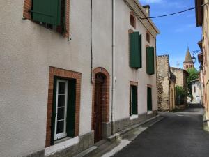 an alley with a building with green shutters on it at Gîte tout Confort au Coeur du Village Verniolle in Verniolle
