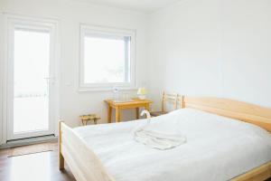 ein weißes Schlafzimmer mit einem großen Bett und zwei Fenstern in der Unterkunft Jurodis in Jurbarkas