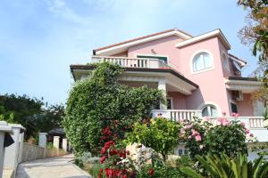 a pink house with flowers in front of it at Apartments Dragun in Podstrana