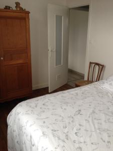 a bedroom with a white bed and a wooden cabinet at Ma maison in Créhen