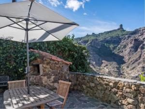 a patio with an umbrella and a table and chair at Casa Rural Pepita La De Las Flores in Tejeda