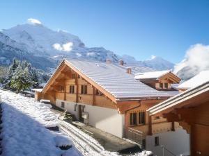 uma casa coberta de neve com montanhas ao fundo em Holiday flat #1, Chalet Aberot, Wengen, Switzerland em Wengen