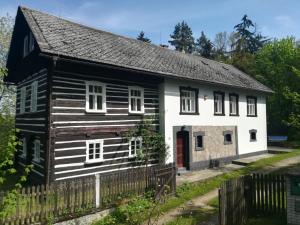 uma casa a preto e branco com uma porta vermelha em Roubenka nad řekou em Noviny pod Ralskem