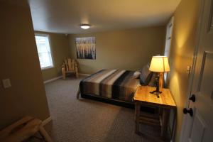 1 dormitorio con 1 cama y 1 mesa con lámpara en Mackinac Lake Trail Motel en Mackinaw City