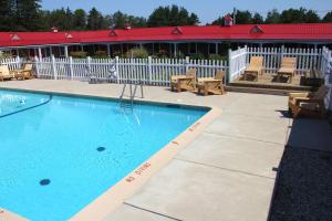 a swimming pool with chairs and a building at Mackinac Lake Trail Motel in Mackinaw City