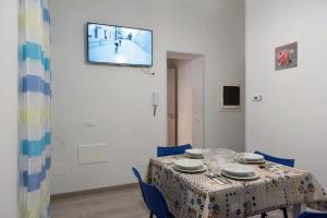 a table with blue chairs and a television on a wall at San Vito Lo Capo da Ciccio in San Vito lo Capo
