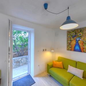sala de estar con sofá verde y ventana en Apartmani Harmonija en Žman