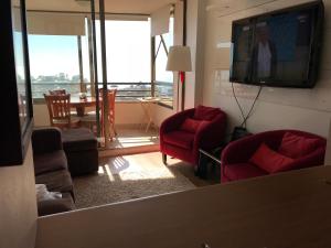 uma sala de estar com cadeiras vermelhas e uma televisão de ecrã plano em Gran departamento con vista al mar em Concón