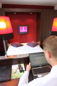a young boy using a laptop computer in a hotel room at Hotel Mijdrecht Marickenland in Mijdrecht