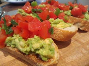 two slices of bread with avocado and tomatoes on a cutting board at Sleep, Eat, Repeat Bed and Breakfast in Macclesfield
