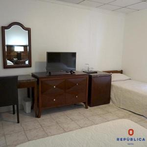 1 dormitorio con 1 cama y vestidor con TV en Hotel República Panamá en Panamá