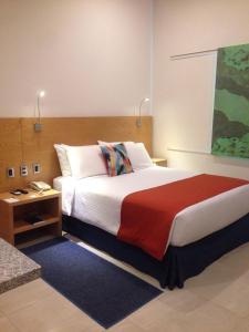 um quarto com uma cama grande e um cobertor vermelho em Hit Hoteles Aeropuerto Puebla em Huejotzingo