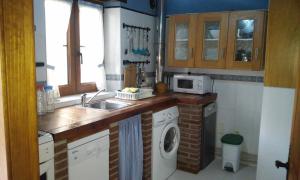 a kitchen with a sink and a washing machine at Casa La Abuela in San Mamés