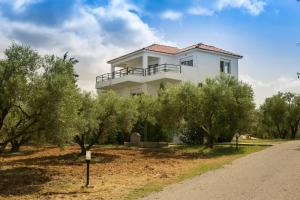 a white house on the side of a road with trees at Kahlenberg apartments in Afitos