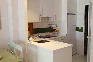 a white kitchen with a sink and a refrigerator at El Cantil in Isla Cristina +10 photos