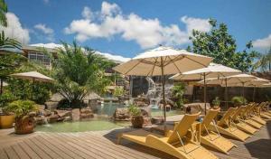 een groep stoelen en parasols naast een zwembad bij Jacana Amazon Wellness Resort in Paramaribo