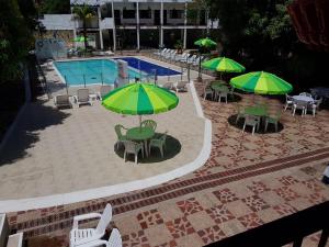 a patio with tables and green umbrellas and a pool at Hotel Villa Maritza in Melgar