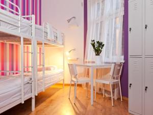 a bedroom with bunk beds and a desk and a table at Blooms Boutique Hostel in Poznań