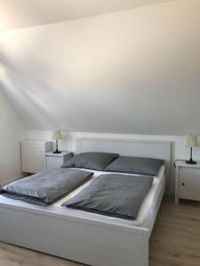 ein weißes Bett in einem Zimmer mit zwei Lampen in der Unterkunft Ferienapartment Kischa in Scharbeutz