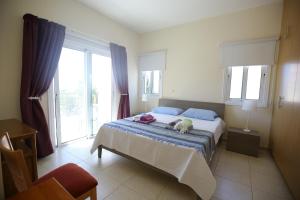 a bedroom with a bed with blue sheets and windows at Unique Beach Luxurious Villas in Ayia Napa