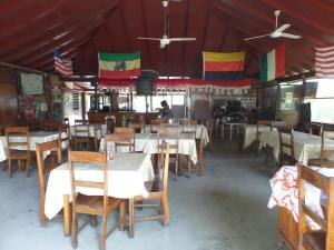 a restaurant with tables and chairs and flags on the ceiling at Jah B's Cottages on Beach Road-Negril in Negril