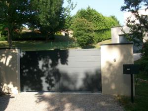 a garage with a white wall and a fence at villa terrefort in Drémil-Lafage