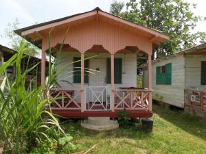 Jah B's Cottages on Beach Road-Negril في نيغريل: منزل صغير مع شرفة في الفناء