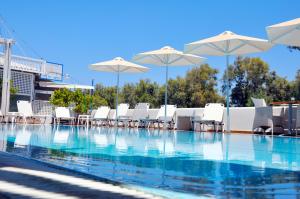 una piscina con sedie e ombrelloni bianchi di Memories Beach Hotel a Monolithos