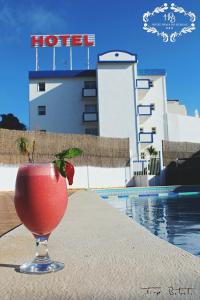 a drink sitting on a table next to a hotel at Hotel Burgau Turismo de Natureza in Burgau